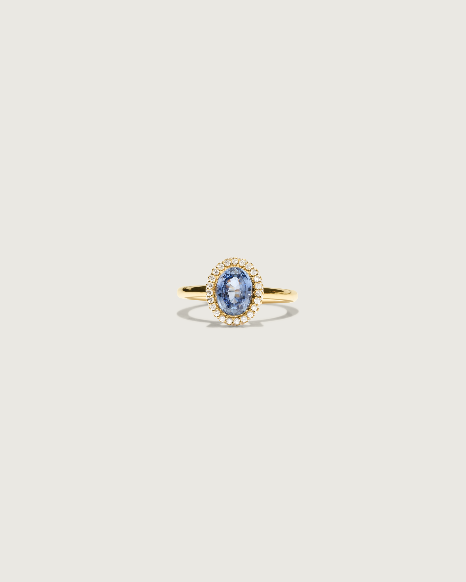 Cecile Bombé verlovingsring in 18k goud met 2,00 ct ovale blauwe saffier en dubbele kroon van witte briljanten op lichte achtergrond